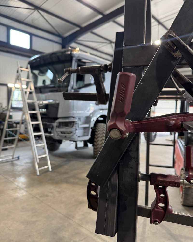Structure en tubes d'acier maintenue par des serre-joints, un porteur MAN en arrière-plan