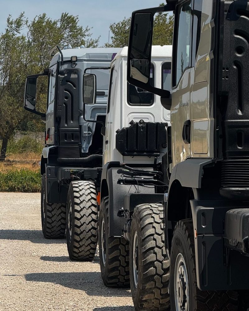 Trois porteurs poids lourds tout-terrain alignés devant l'atelier