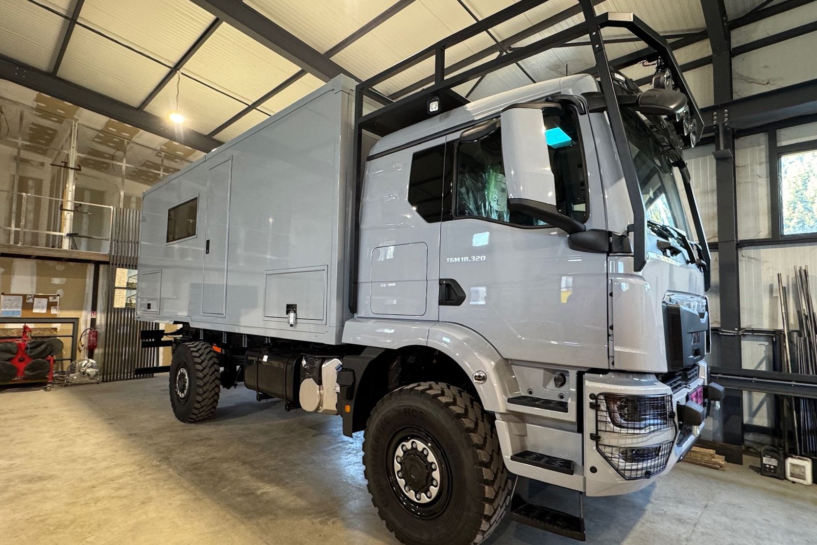 Camion d'expédition MAN TGM 18.320 4x4 gris avec cellule d'habitation et galerie de toit, dans l'atelier HDSB